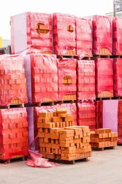 Red clay bricks stacked on pallets Stockfoto's