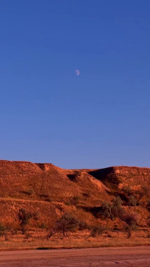 Red Clay Cliffs and Daytime Moon in Clear Blue Sky Stockbeeldmateriaal 345123986