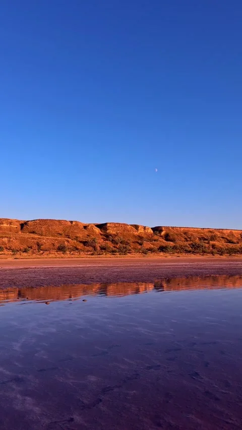 Red Clay Cliffs Reflection on Still Estuary Water with Moon Stockbeeldmateriaal 345124013