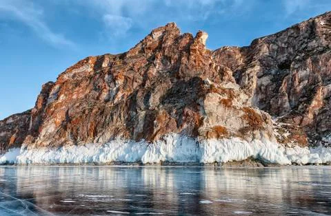 Red cliff, bordered by white ice on lake Baikal Stock Photos