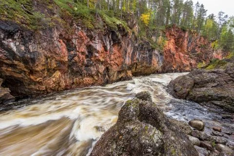 Red cliff, stone wall, forest, waterfall and wild river view in autumn. Fall  Foto stock