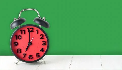 Red Clock on green background with copy space. Stock Photos