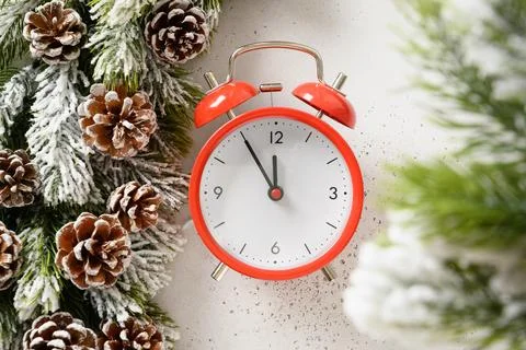 Red clock shows the New Year is coming. New Year's concept with evergreen b.. Stock Photos