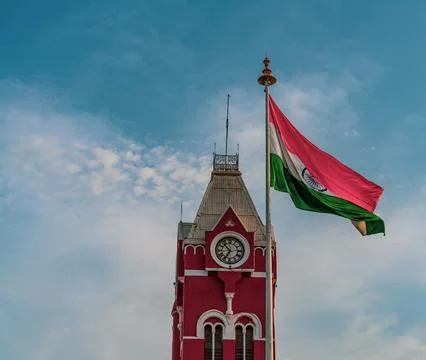 A red clock tower with a flag on top. in Chennai Stock Photos