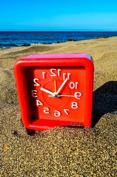 A red clock with white numbers on a beach Foto stock