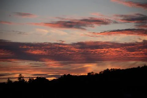 Red clouds lit up by the sun at sunset. Stock Photos