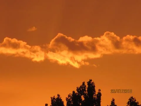 Red clouds at sunset, on a blue-gray sky background Stock Photos