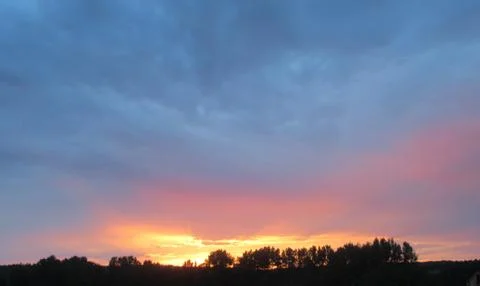 Red clouds at sunset, on a blue-gray sky background Stock Photos