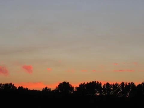 Red clouds at sunset, on a blue-gray sky background Stock Photos
