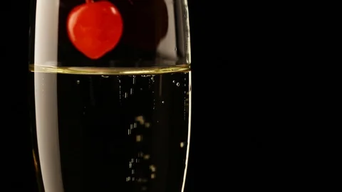 Red cocktail cherry falling in glass of champagne Stock Footage 100417509
