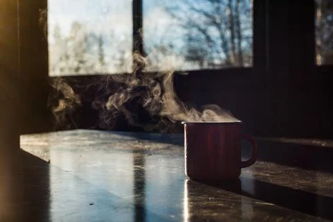 A red coffee mug sits on the table, steaming Stock Photos