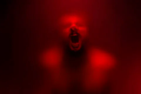 Red color filter version of Creepy man screaming behind the frosted glass. Stock Photos