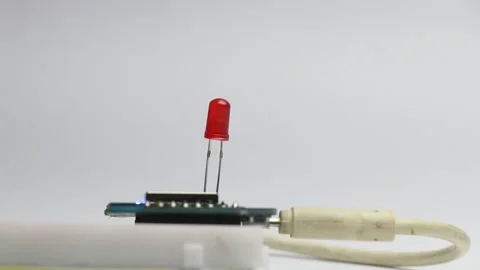 Red color led blinking on a breadboard connected to a microcontroller Stock Footage 327978512