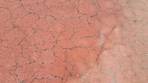 Red colored damaged road or paved pathway with crackes of different shpaes. C Stock Photos