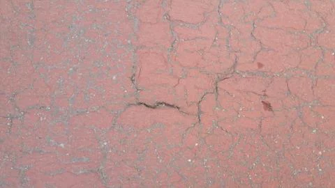 Red colored damaged road or paved pathway with crackes of different shpaes. C Stock Photos