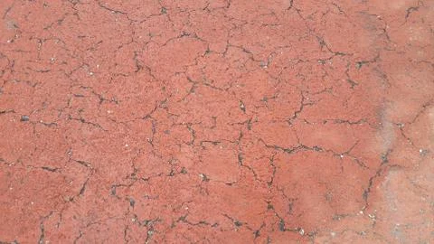 Red colored damaged road or paved pathway with crackes of different shpaes. C Stock Photos
