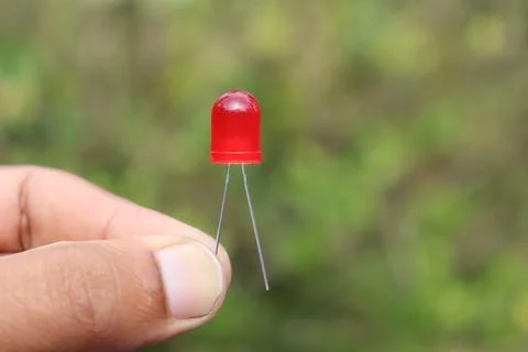 Red colored LED or light emitting diode held in the hand on nature background Stock Photos