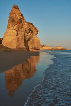 Red colored limestone rock reflecting in the low tide water. Praia do Amado i Foto stock