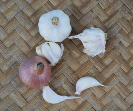 A red colored medium sized fresh onion and some white garlic beside some scat Stock Photos