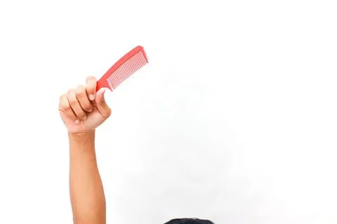 A red comb held high on a pristine white backdrop symbolizing beauty routine Stock Photos