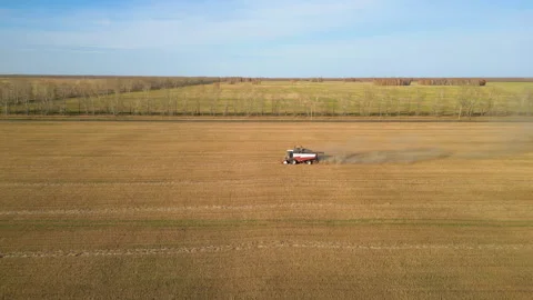 Red combine harvester working on a wheat field leaving a trail of dust Stock Footage 287103497