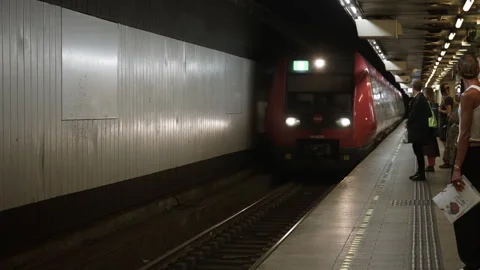 Red commuter train arrives at an underground station platform with passengers Stock Footage 344956854