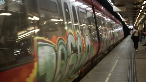 Red commuter train with graffiti arriving at underground station platform Stock Footage 344956563