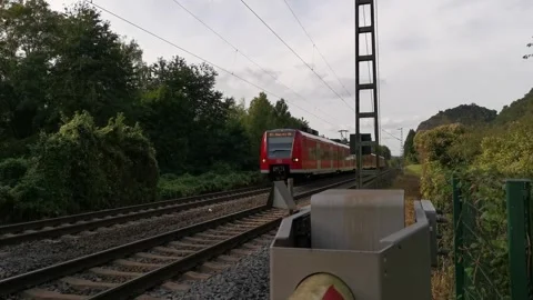 Red commuter train passing a level crossing Stock Footage 306933323
