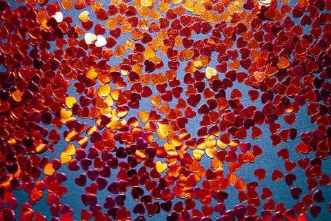 Red confetti on a red background Stock Photos