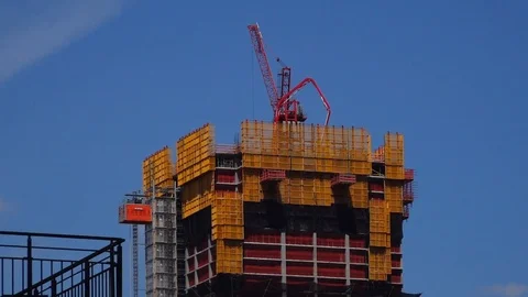 Red construction crane pouring cement on high rise building Stock Footage 114083868