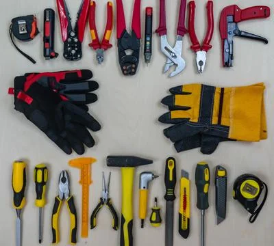 A red construction tool vs a yellow working tool on a plywood background. Stock Photos
