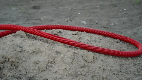 Red corrugated protective pipes lying on dry uneven dirt ground Stock Footage 337123065