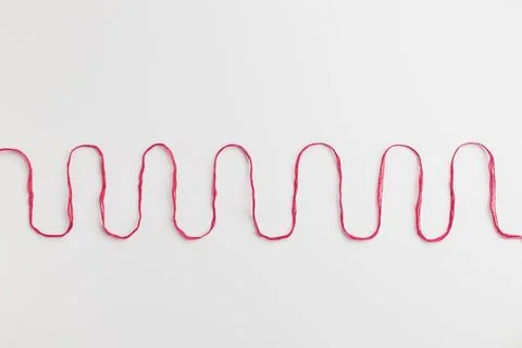 Red cotton thread as a wave on a white background Stock Photos