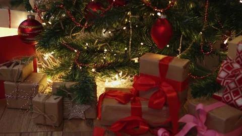 Red craft gift boxes under decorated Christmas tree blinking new year eve lights Video stock 164594869