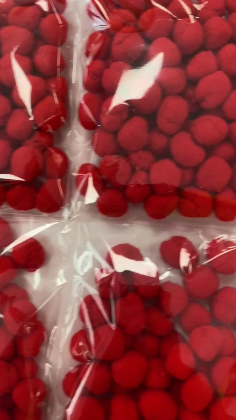 Red craft pom poms packed in transparent plastic bags for DIY projects Stock Footage 317578304
