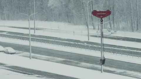 Red crane hook with bucket over a snowy road, during heavy winter snowfall, Stock Footage 325698954