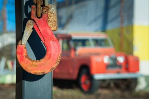 Red crane hook with oldtimer offroad vehicle in the blurry back Red crane ... Fotos de archivo