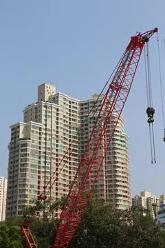 A red crane lifting a heavy object in front of apartment buildings, showcas.. Stock Photos