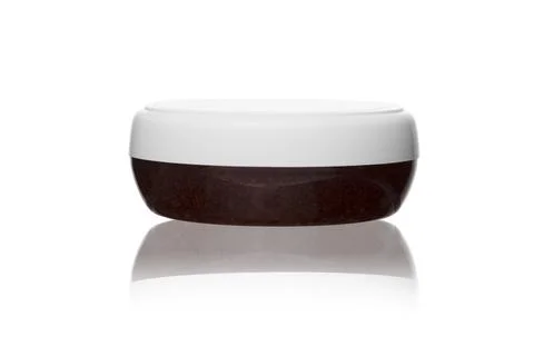 Red cream souffle or scrub in transparent plastic jar with white lid on white Fotos de archivo