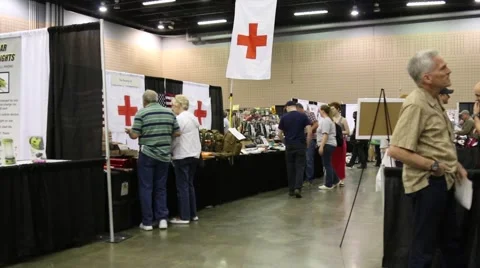 Red Cross/First Aid Banner over Table at Doomsday Prepper Convention Stock Footage 64907712