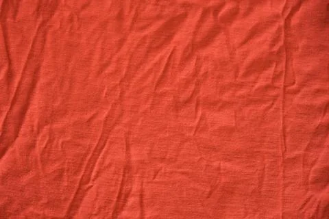 Red crumpled textile material. Texture or background. Stock Photos