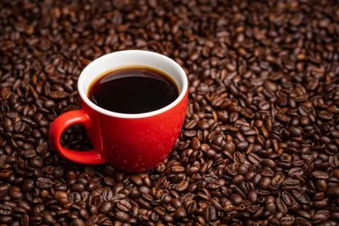 Red Cup of black coffee on table covered with coffee beans. Stock Photos