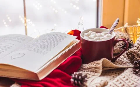 Red Cup with cocoa and marshmallows on a wooden table with scarves old book h Stock Photos