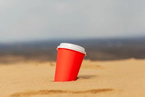 A red cup of coffee or a hot drink in the sand in the desert. Stock Photos