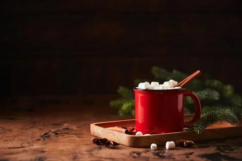 Red cup of hot cocoa with marshmallows on wooden table with christmas tree fo Stock Photos