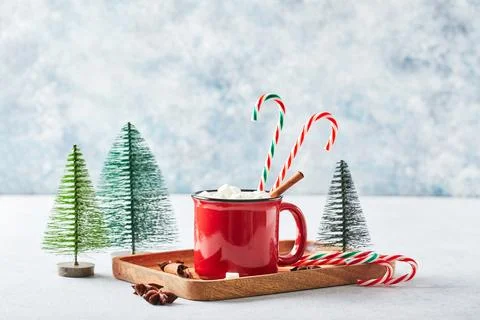 Red cup of hot cocoa with marshmallows and candy canes on with christmas tree Stock Photos