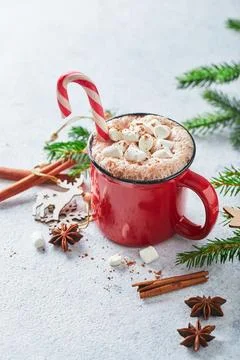 Red cup of hot cocoa with marshmallows and candy canes on with christmas tree Stock Photos
