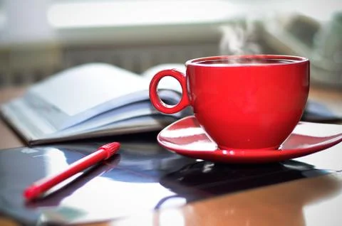 Red cup of hot coffee, notepad and pencil on the desktop in the office.  Stock Photos
