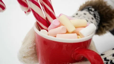 Red cup with marshmallows and striped sweets in hands against a background of Video stock 168121728