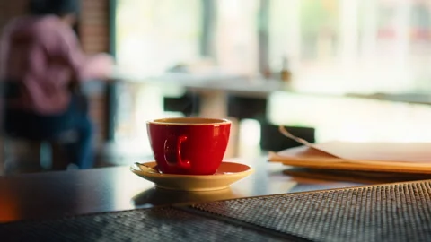 Red cup of steaming hot coffee on table in cafe Video stock 206691698